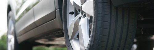 View of the new tires and modern aluminum trim of a parked SUV, shot from below, photo developed in raw format as a black and white image